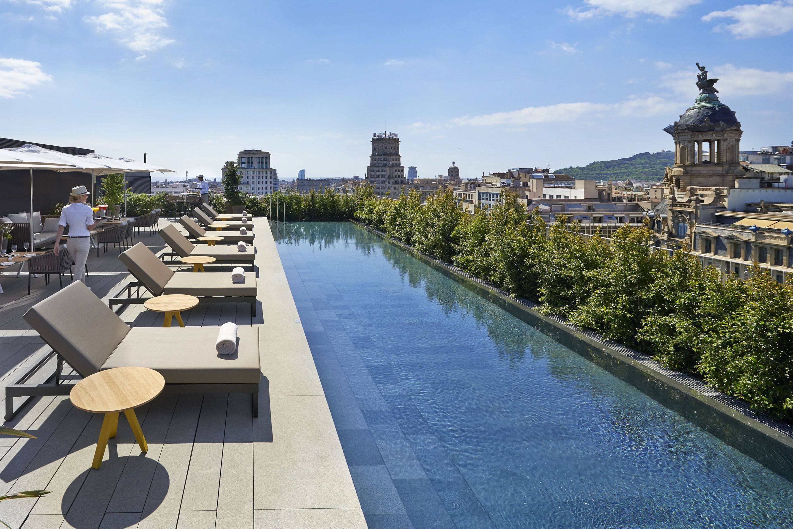 A woman practices yoga on a rooftop pool overlooking the city.