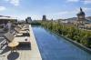 A woman practices yoga on a rooftop pool overlooking the city.