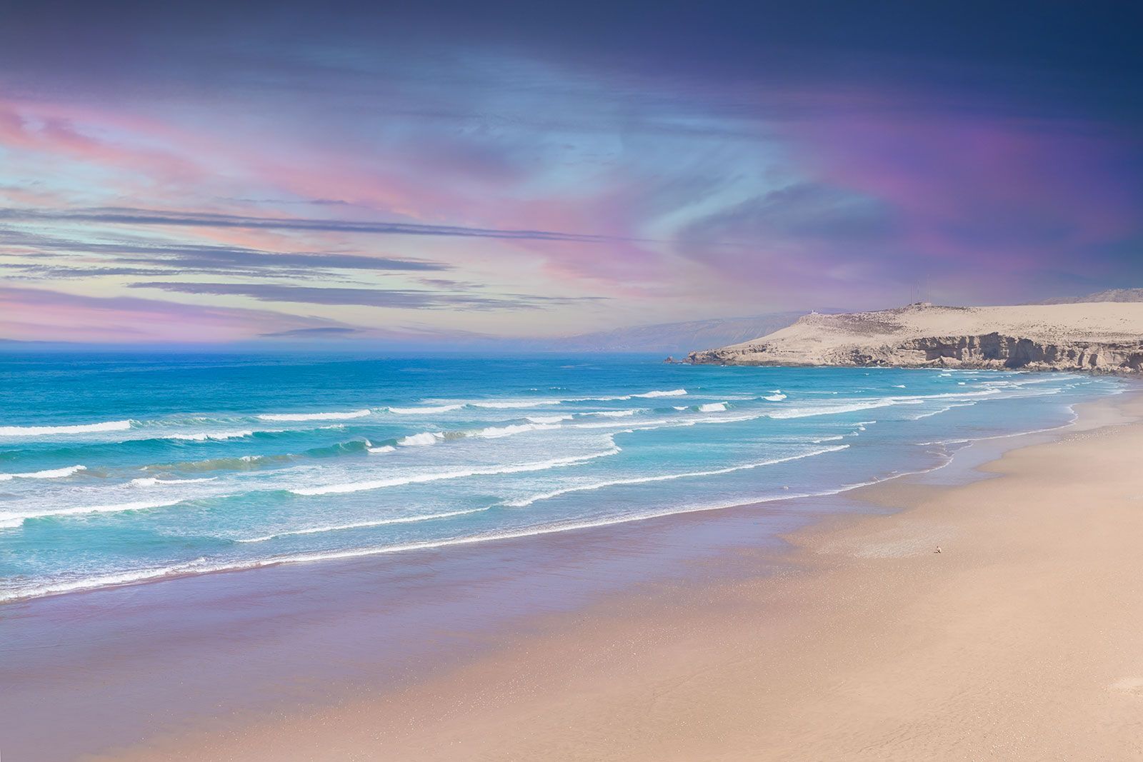 Curving shoreline with blue waves and hazy sky 