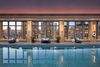 An indoor pool with floor-to-ceiling windows and a view of the New York City skyline.