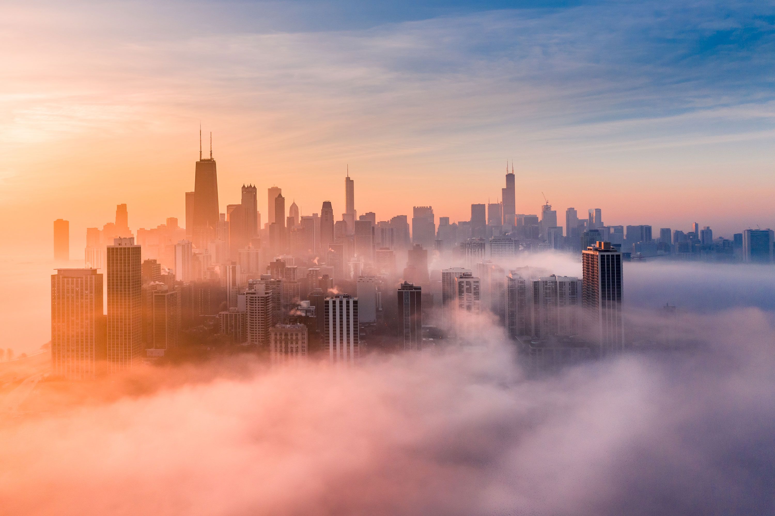 Skyline of Chicago with fog surrounding buildings during a sunset.