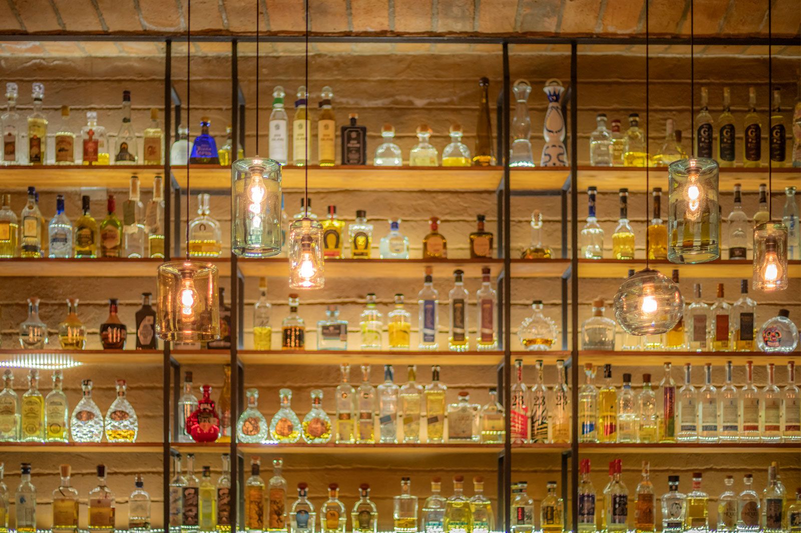 A picture of bar shelf with bottles of various spirits.  