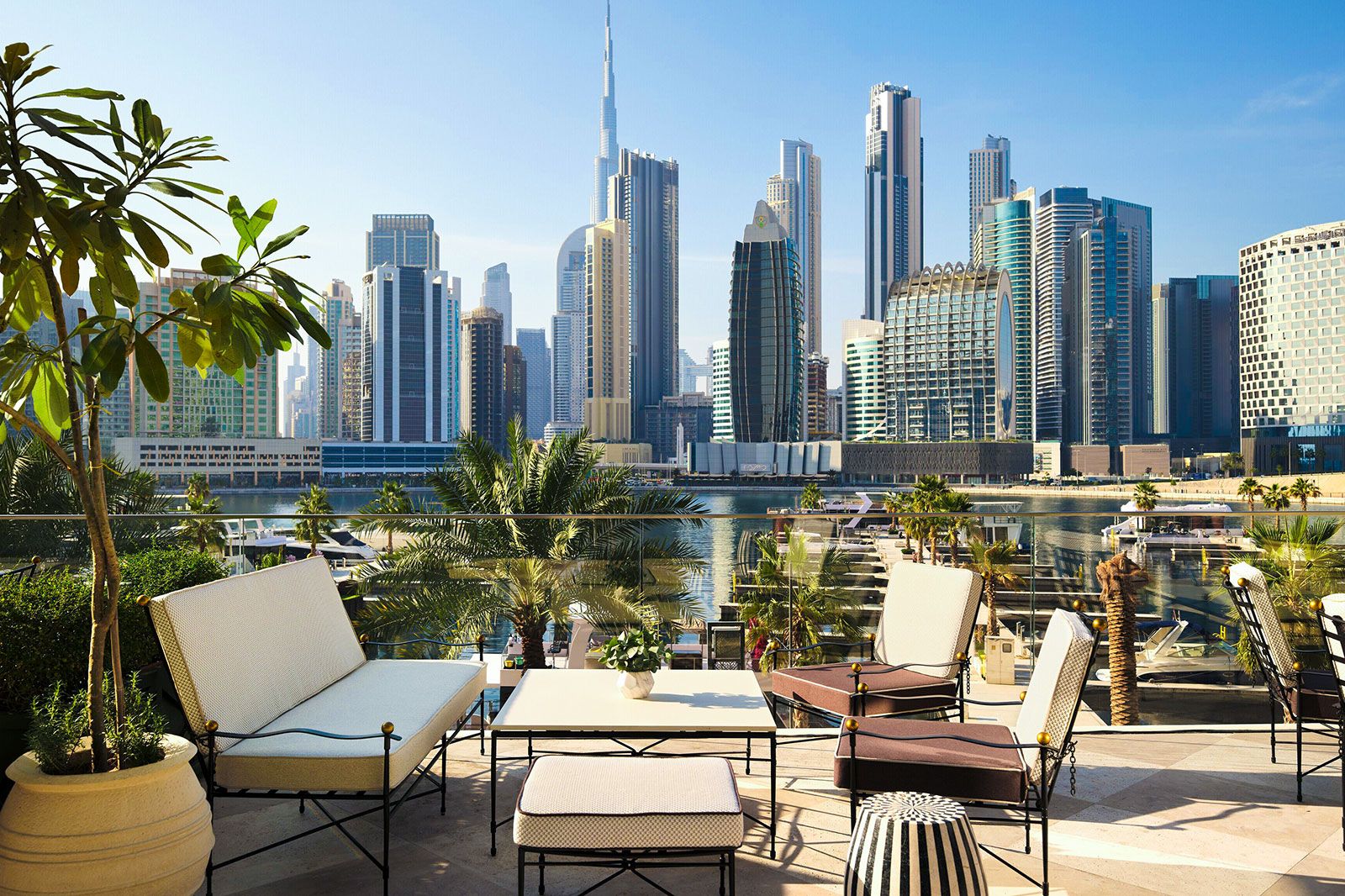 A woman standing with a drink in her hand next to a glass window and looking out.