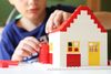 A kid building a red and white lego house.