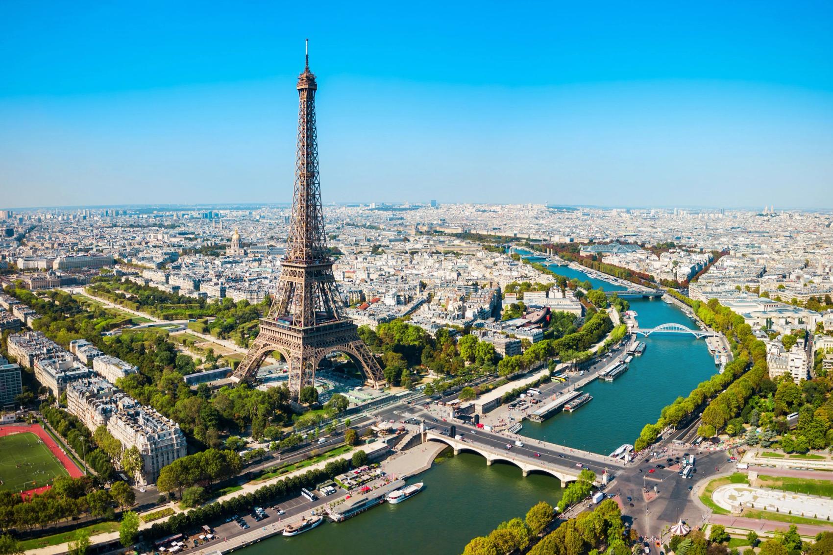 Aerial view of the Eiffel Tower and the river cutting through the city of Paris.