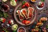 A plate of Tacos with assorted vegetables around.
