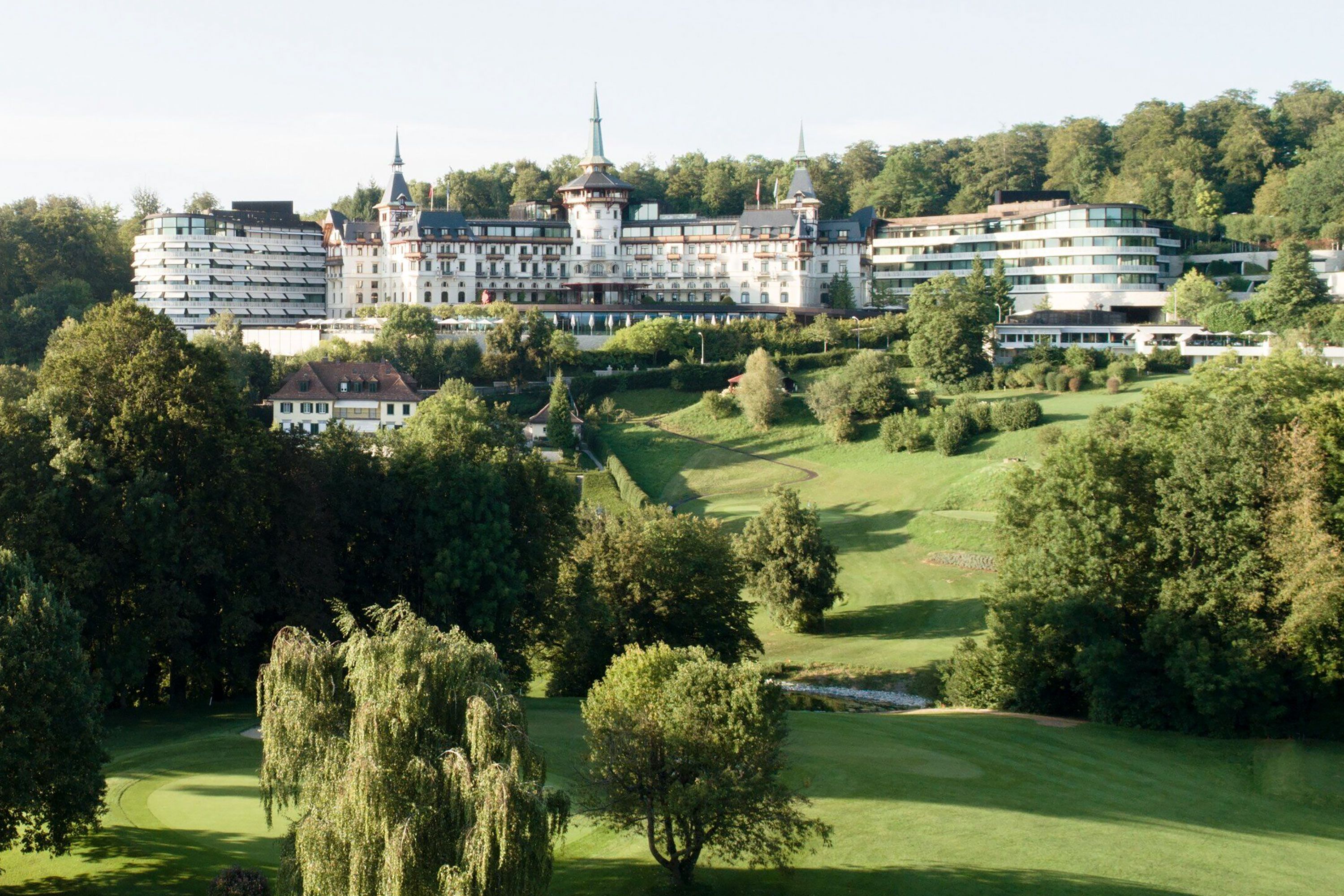 Exterior of The Dolder Grand in Switzerland with grand historic architecture and green hillside setting.