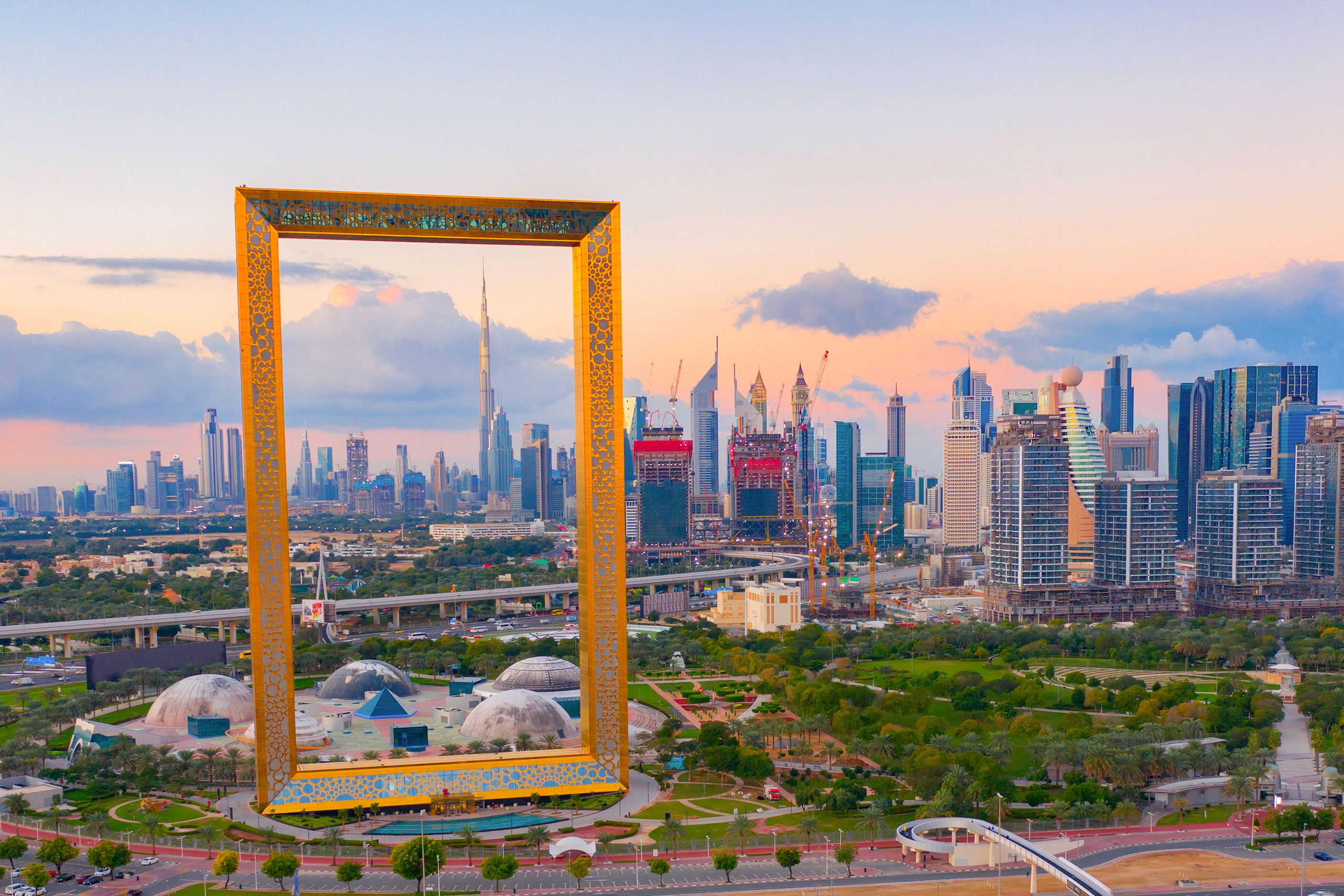 Aerial view of Dubai Frame with downtown skyline and skyscrapers at sunset.