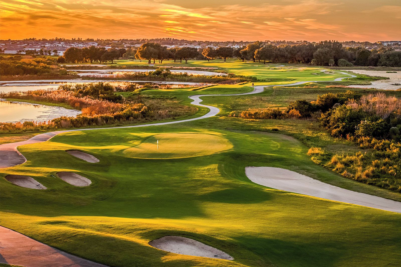 The low sun shines over a golf course.