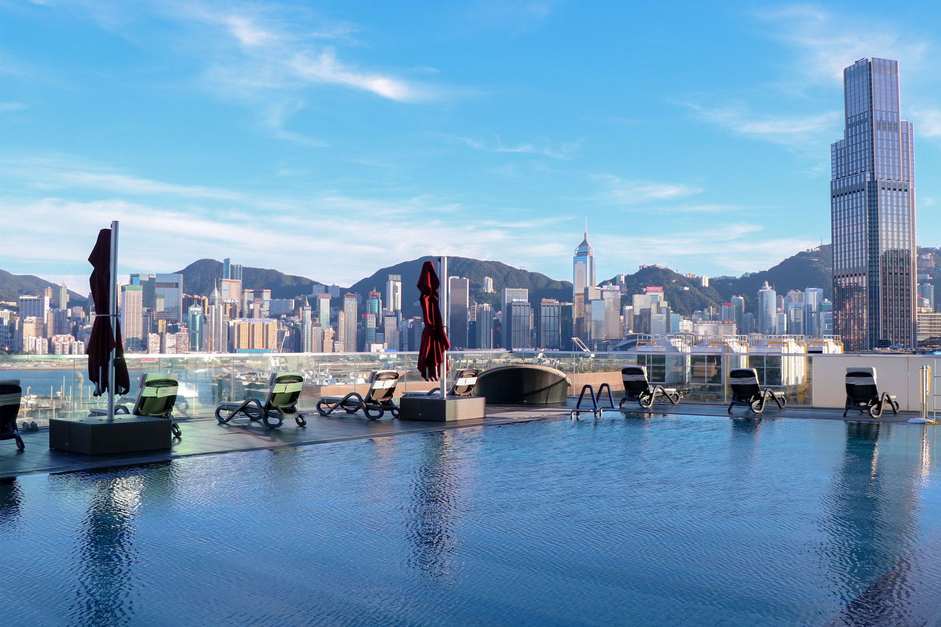 An outdoor rooftop pool with loungers looking out at the city.