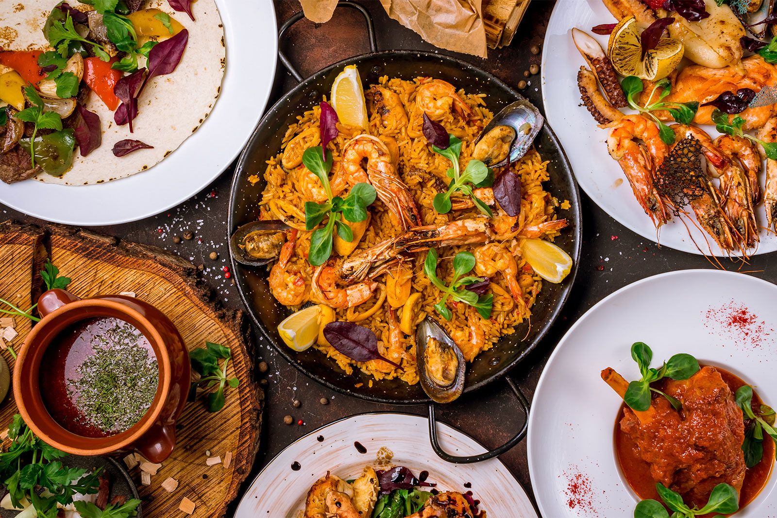 A seafood paella and assorted Spanish food on a table.