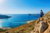 From a rocky perch a hiker with his camera looks out over a seascape featuring a small collection of islands.