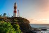 A red-and-white lighthouse on top of a cliff.