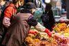 A shopkeeper picking up pickled vegetables at a market.