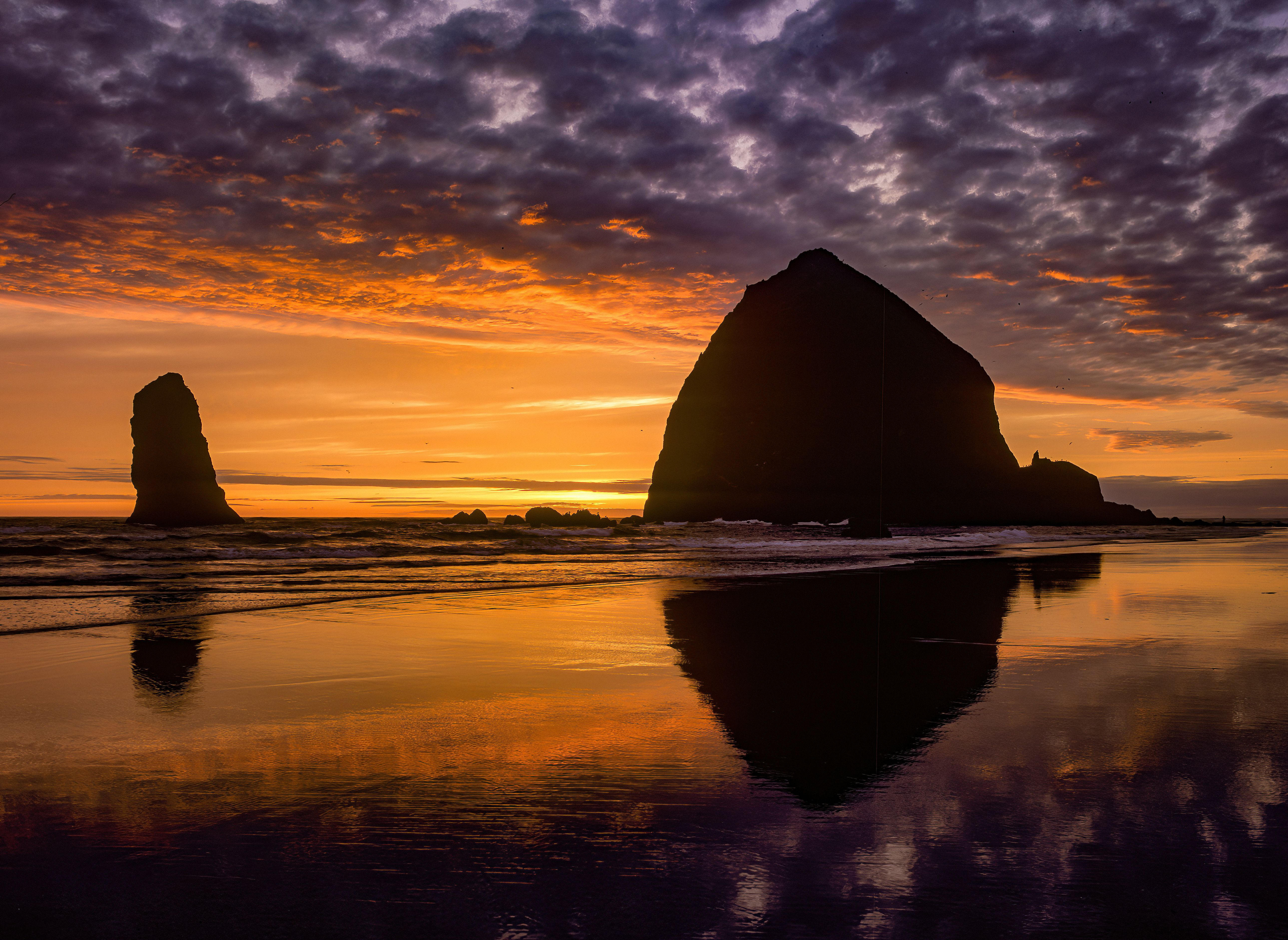 A silhouette of beach with a monolithic rock during sunset. 