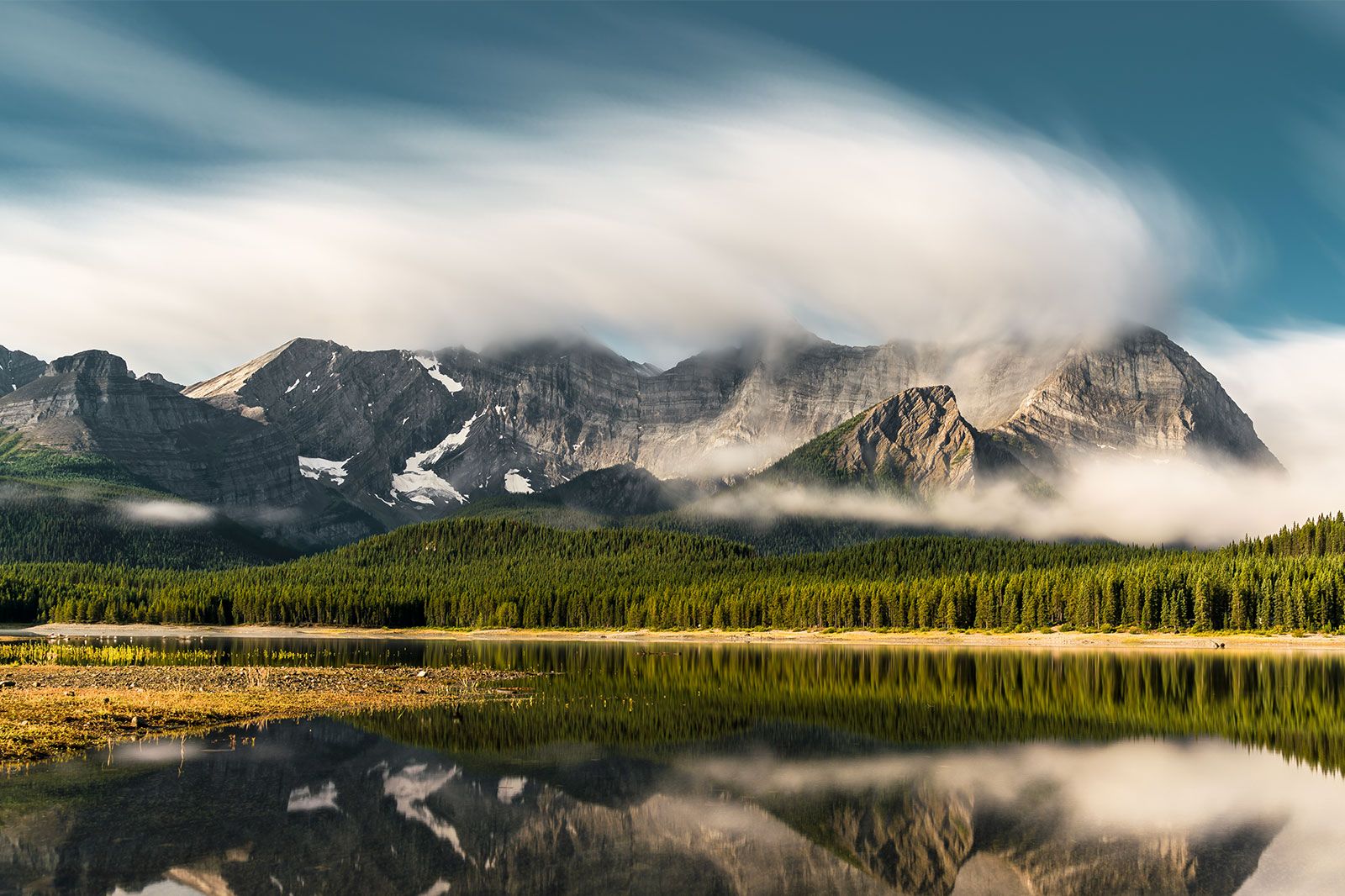 Reflection in a lake of mountains with low hanging clouds.