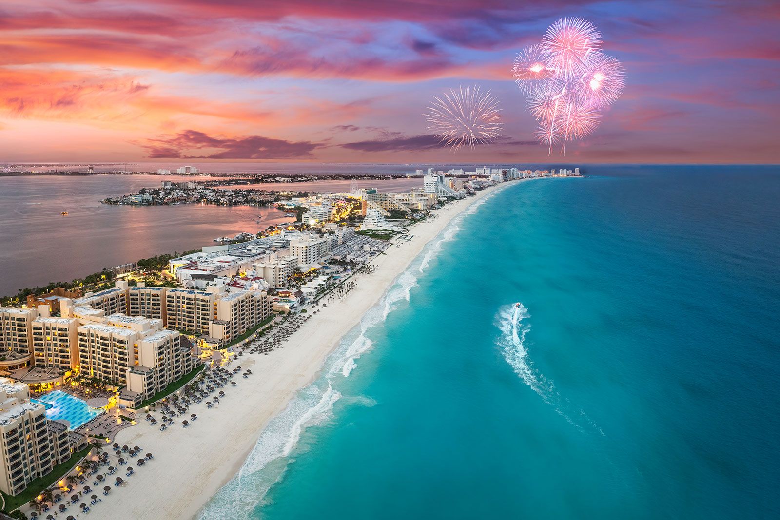 An island city beach and fireworks in the sky at the sunset.