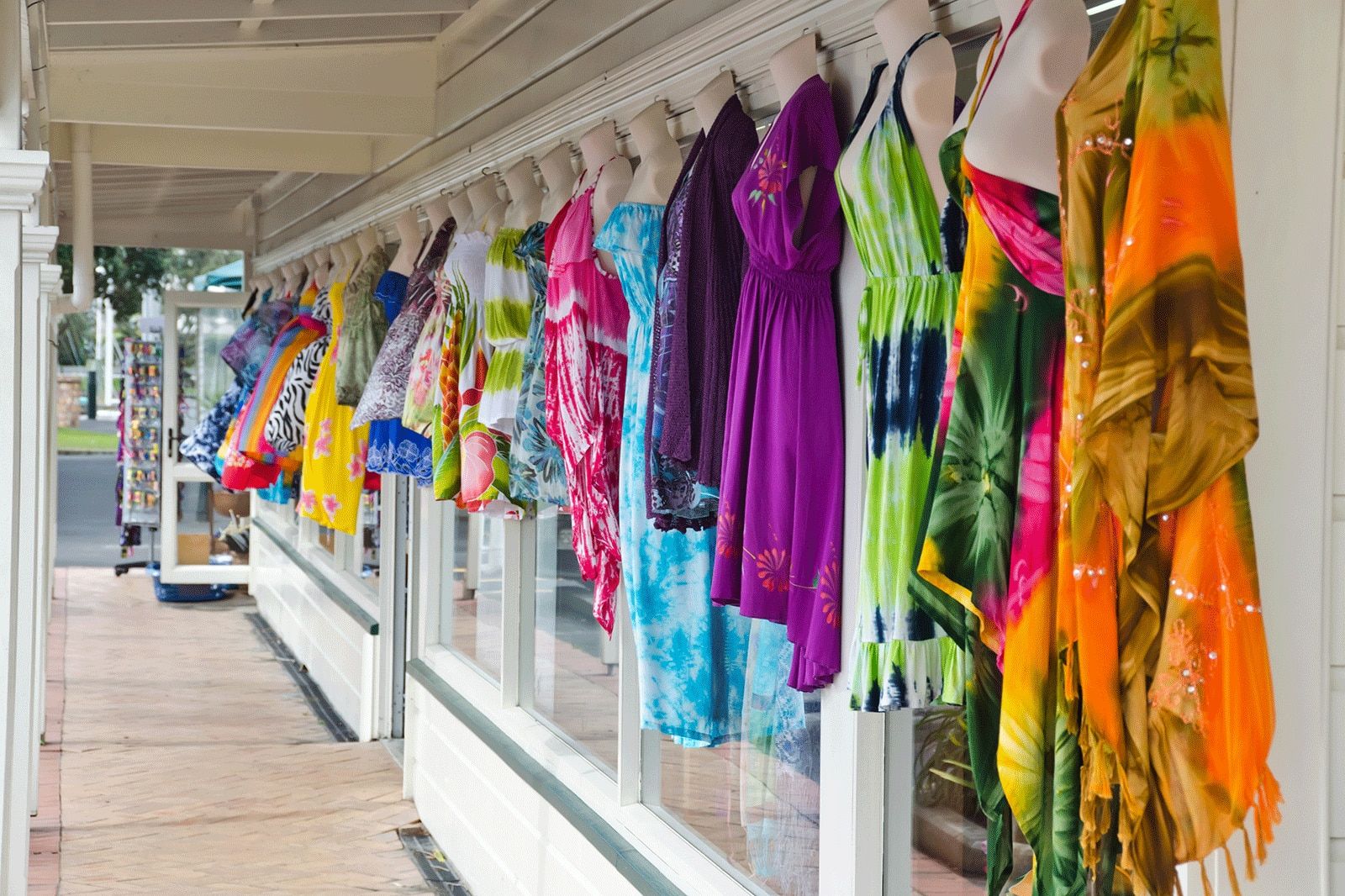 Row of colorful beach dresses hanging outside.