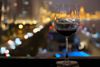 A glass of wine on a table in a rooftop bar.