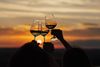 Three wine glasses clinked together at sunset.