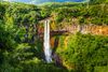 A tall waterfall surrounded by green vegetation.