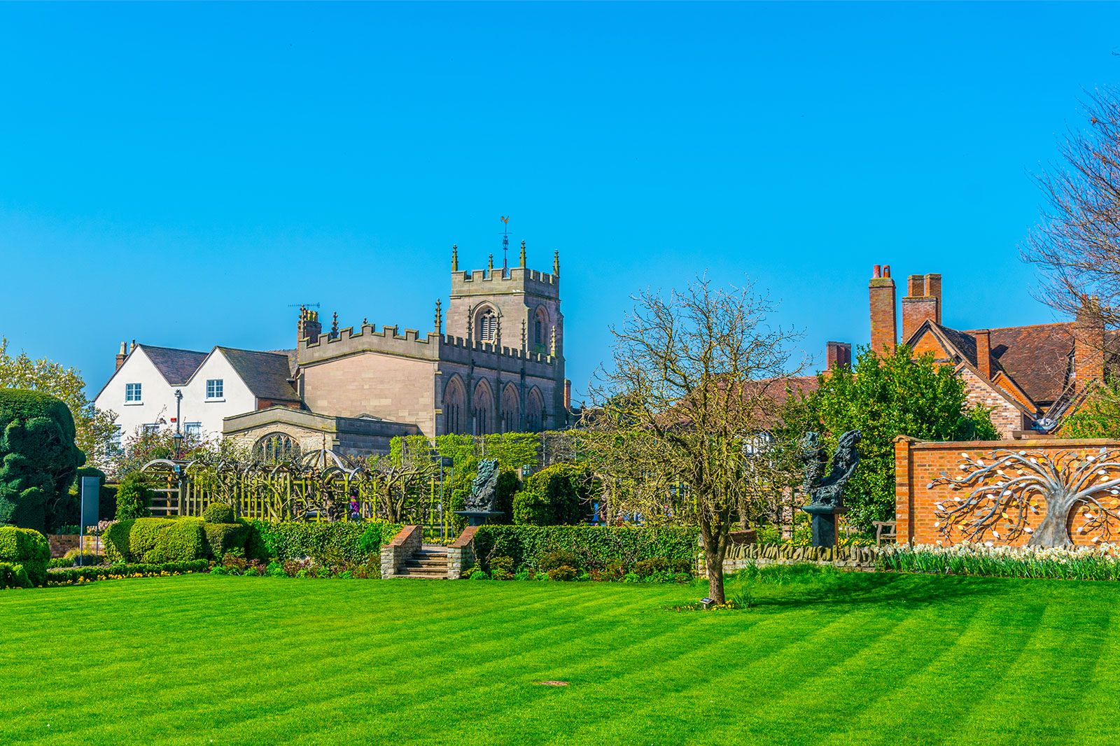 A view of gardens and old buildings among green grass.
