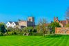 A view of gardens and old buildings among green grass.