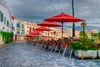 Red umbrellas at seats at a resturant along a town square.