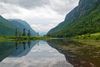 A lake and green mountains and trees in the distance.
