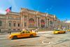 Iconic yellow cabs in front of a grand old building.