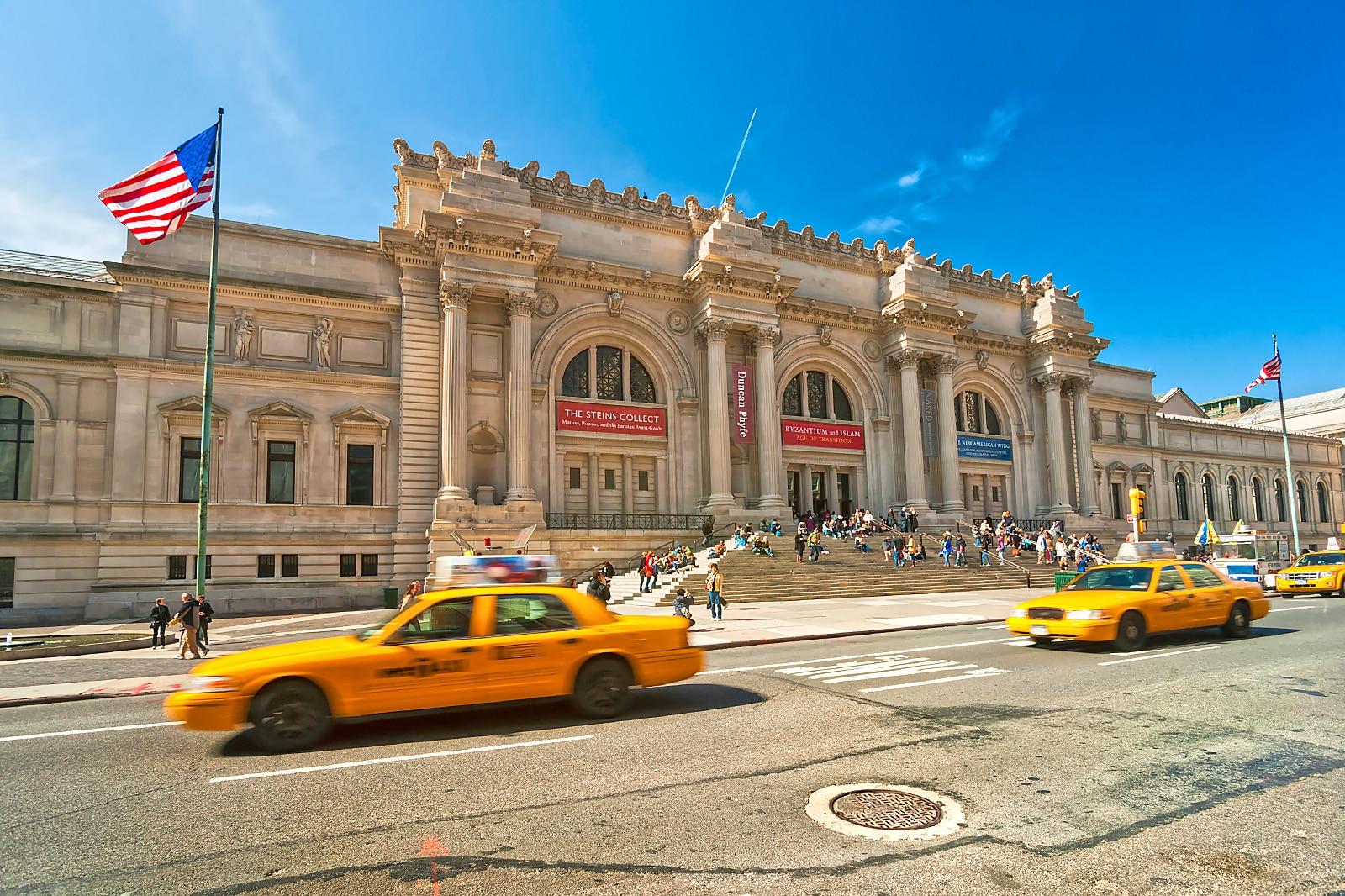 Iconic yellow cabs in front of a grand old building.