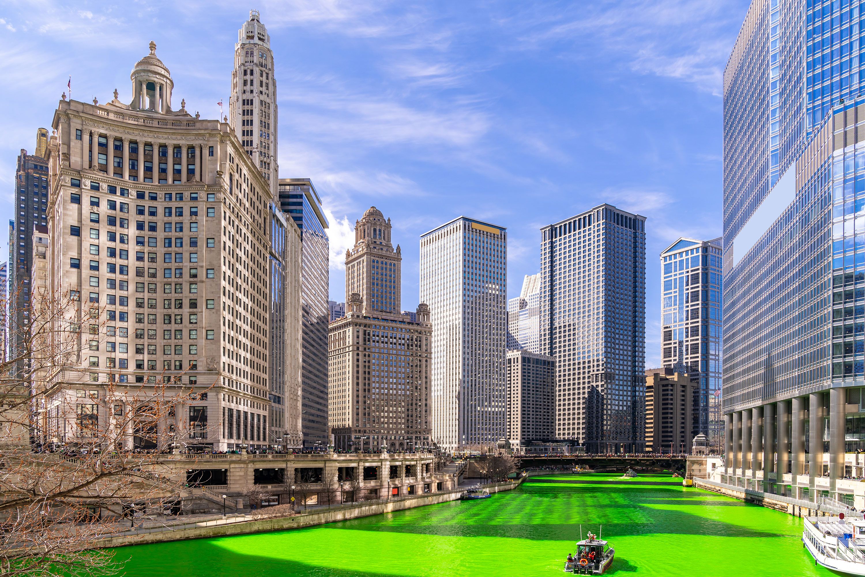 Boats float down a bright green river in the city.