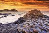 A sunset view of rocks on a coastline.