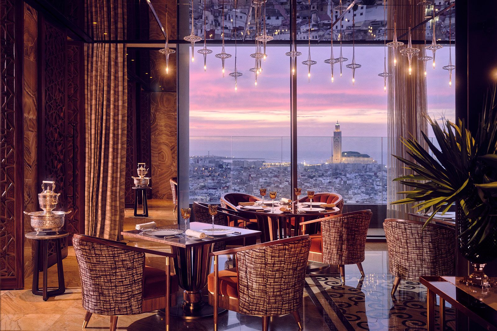 Tables and chairs at a restaurant with a large window looking over a city. 
