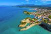An aerial view of rock peninsulas from a coastal town shoreline.