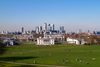 A view of Greenwich Park with the Queen’s House in front and Canary Wharf skyscrapers in the background on a clear day.