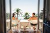 Two people sitting on a balcony overlooking the ocean.