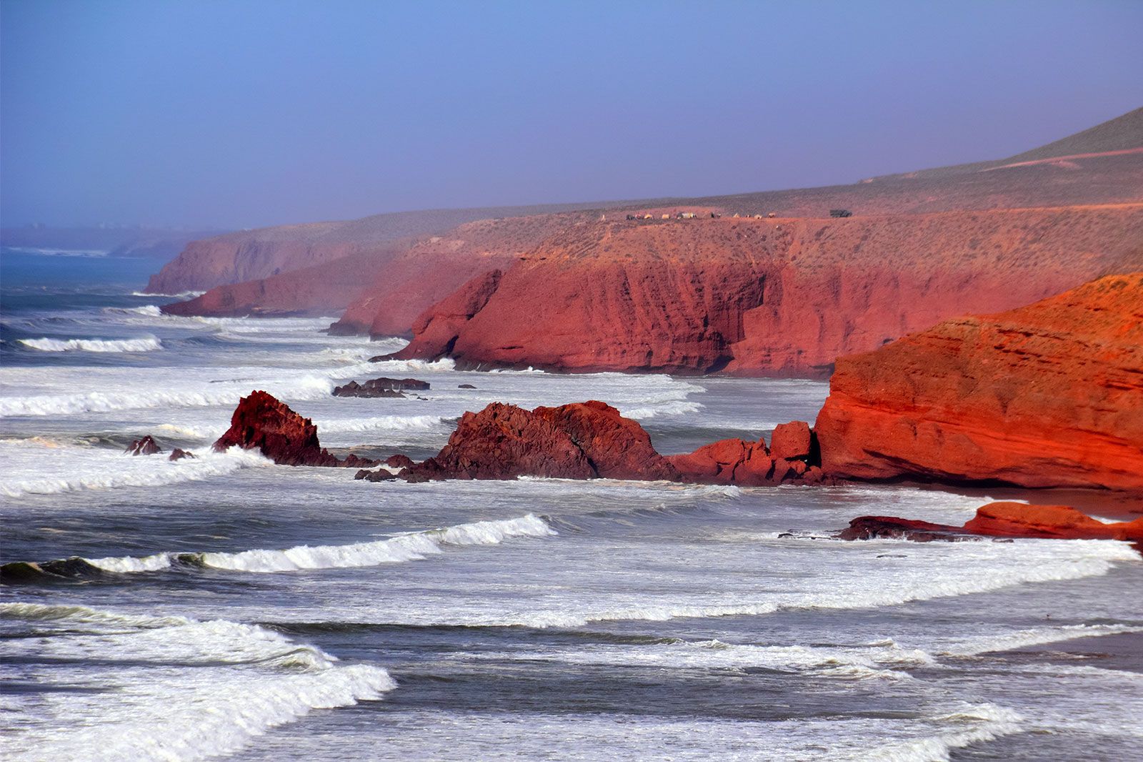 Red stone cliffs along a rocky beach.