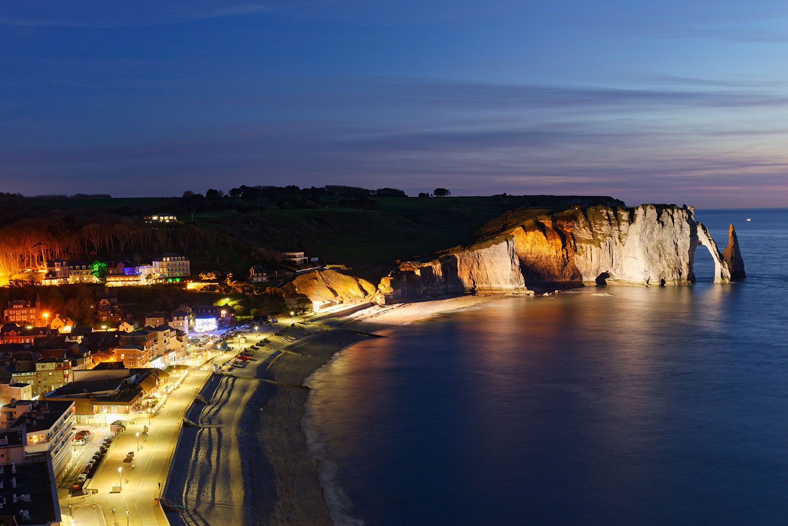 A port with a cliff lit by lights at night.
