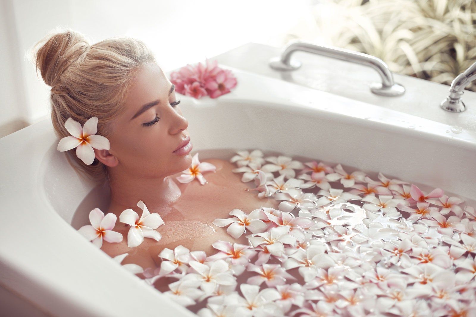 A woman in a tub full of flowers. 