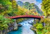 The sacred Shinkyo Bridge at the entrance of Nikko’s shrines with fall foliage in the background.