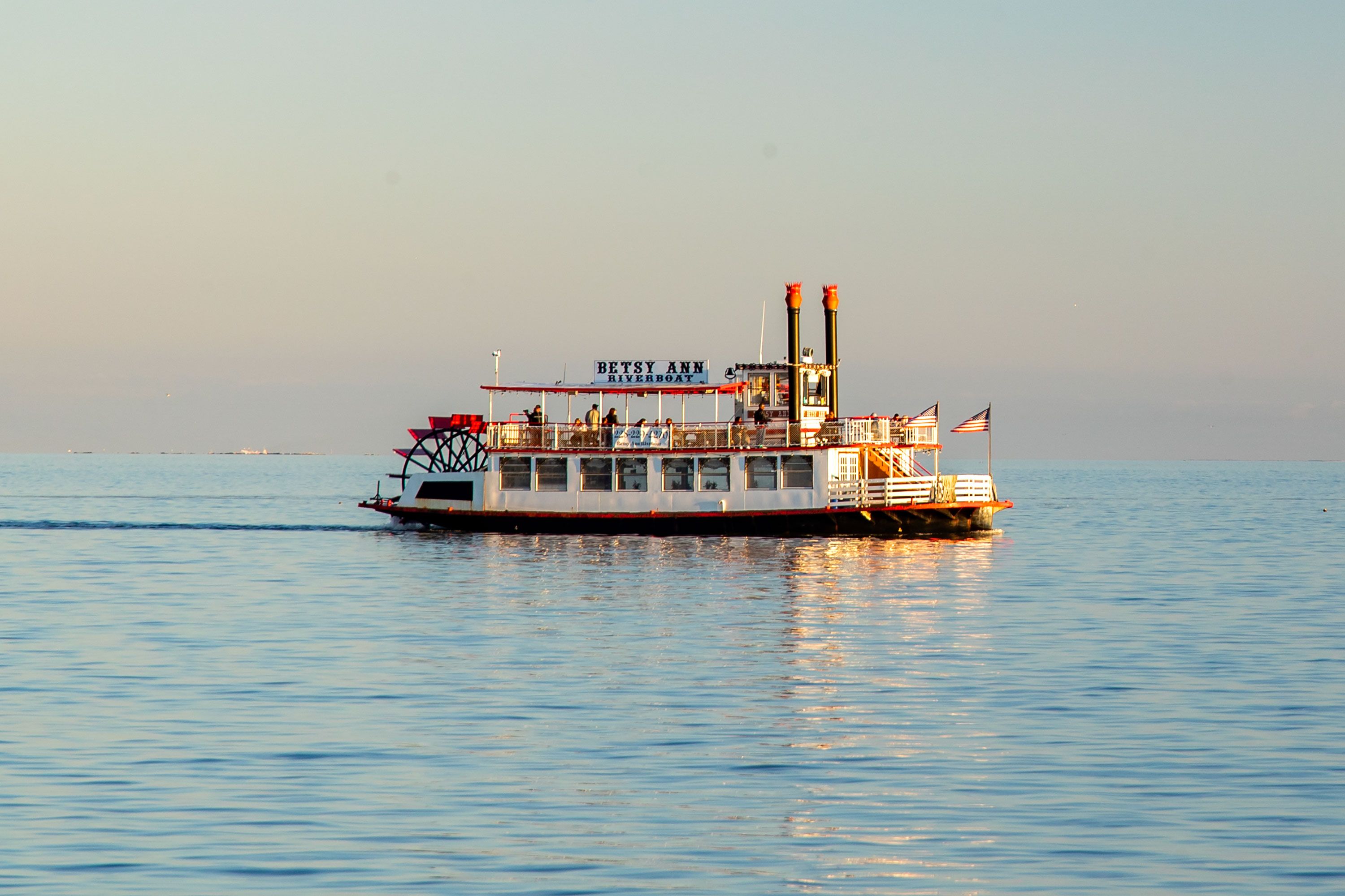 A riverboat floats down a clear calm river.