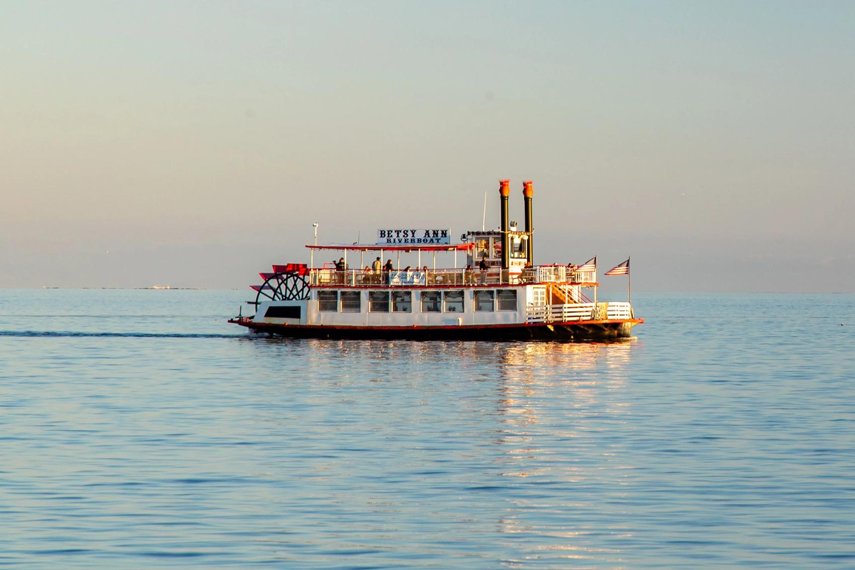 A riverboat floats down a clear calm river.