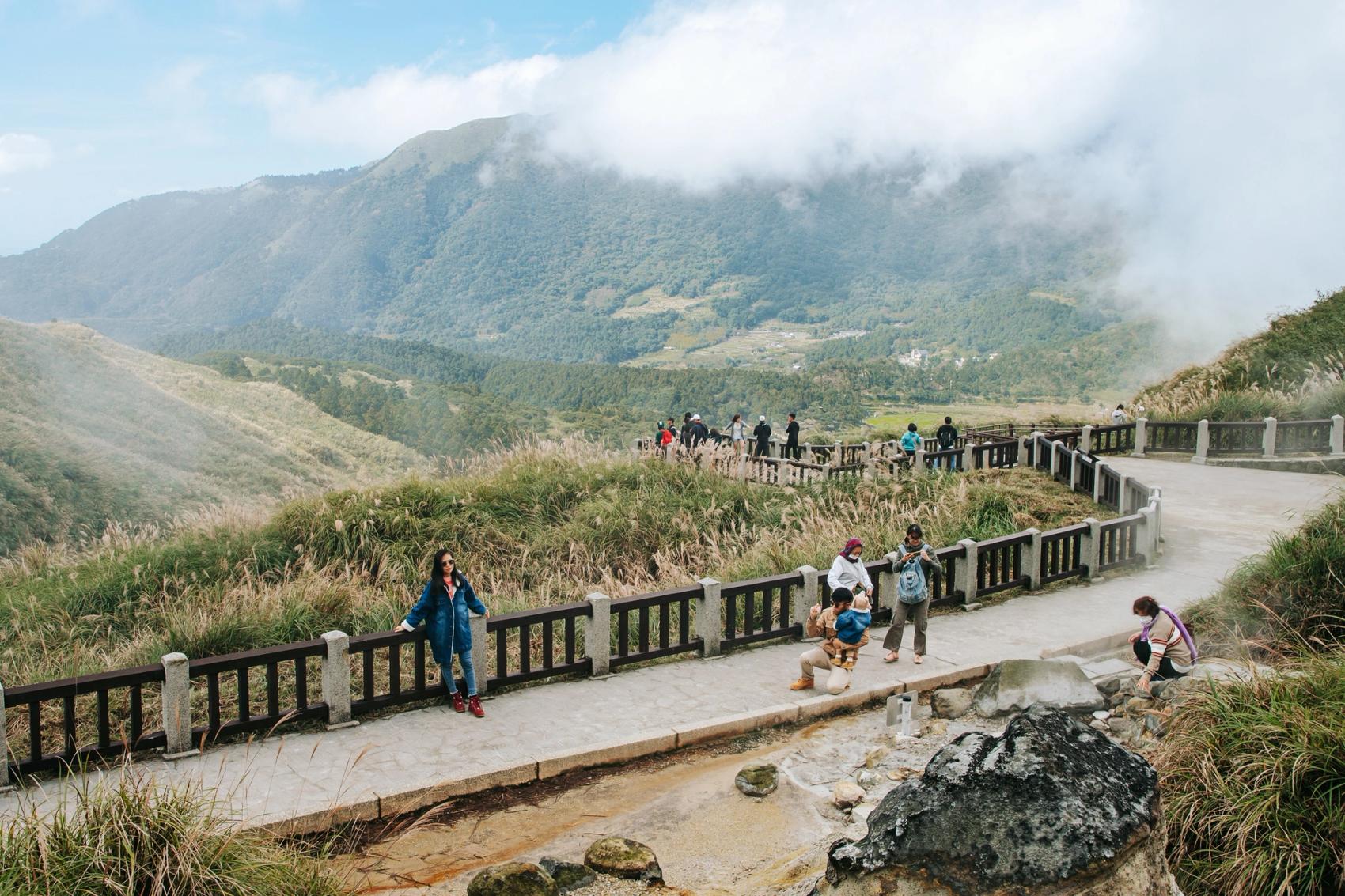 People posing for photo on a walkway overlooking the mountains in Yangmingshan Nation Park in Taipei.