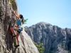 A woman climbs a rock side.