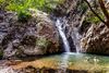 People swim under a waterfall.