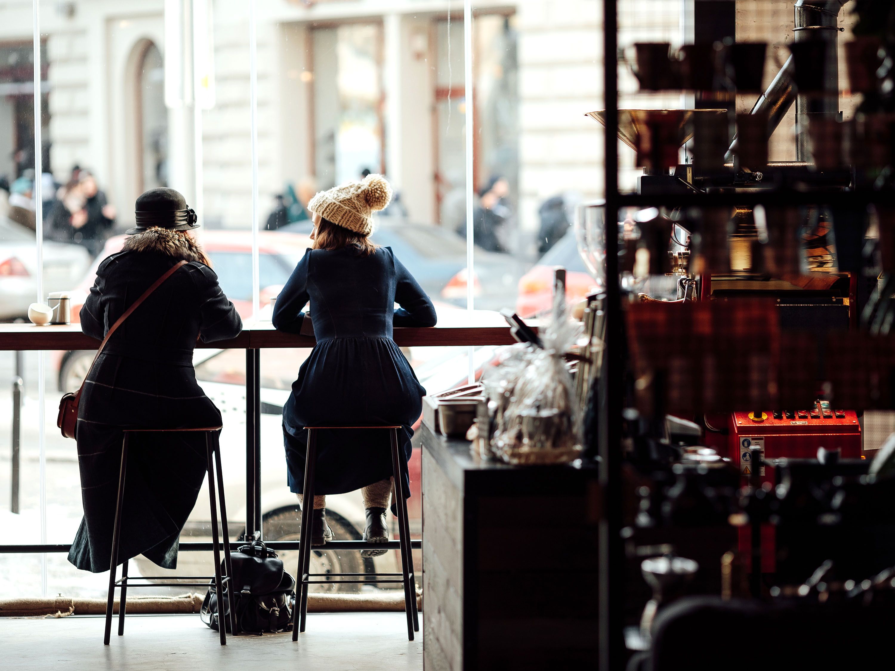 Two women sit at a counter in a cafe