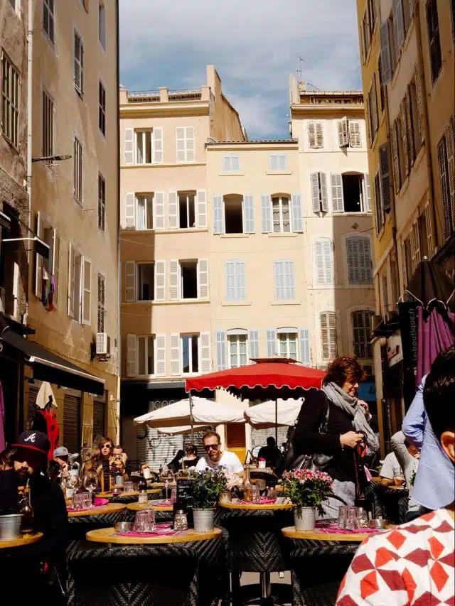 Sun shines on tall buildings around a bustling market street in Nice, France