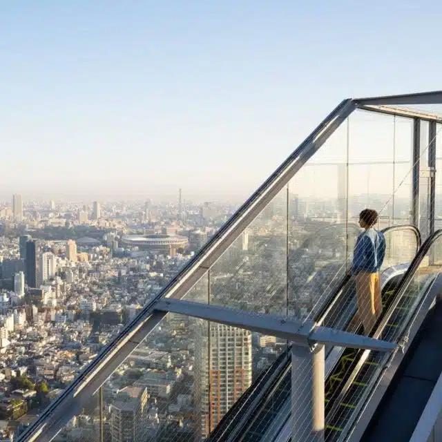 A person rides up the glass-sided Shibuya Sky Escalator in Tokyo, Japan