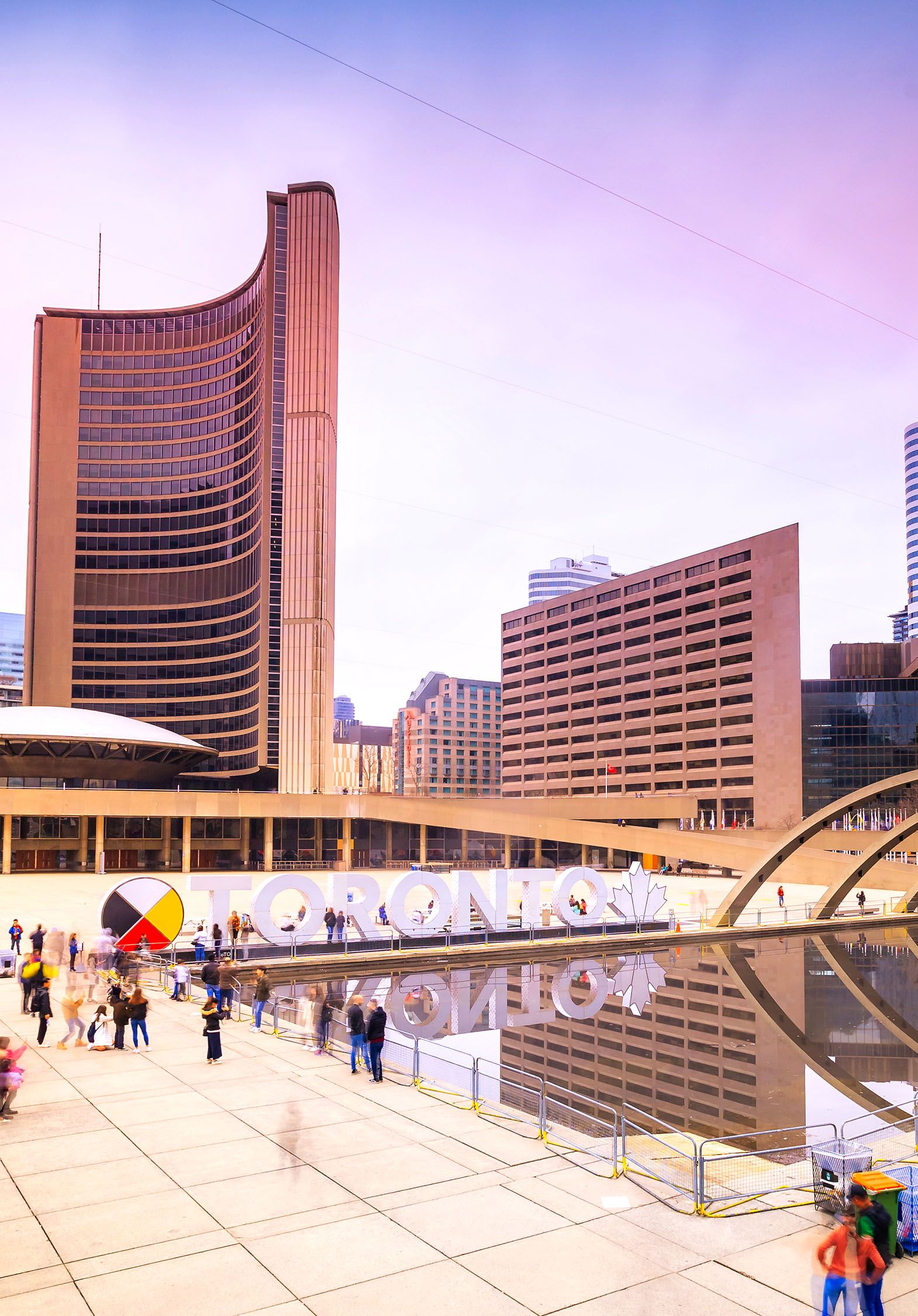 Overview photo of people in a plaza area surrounded by tall buildings.